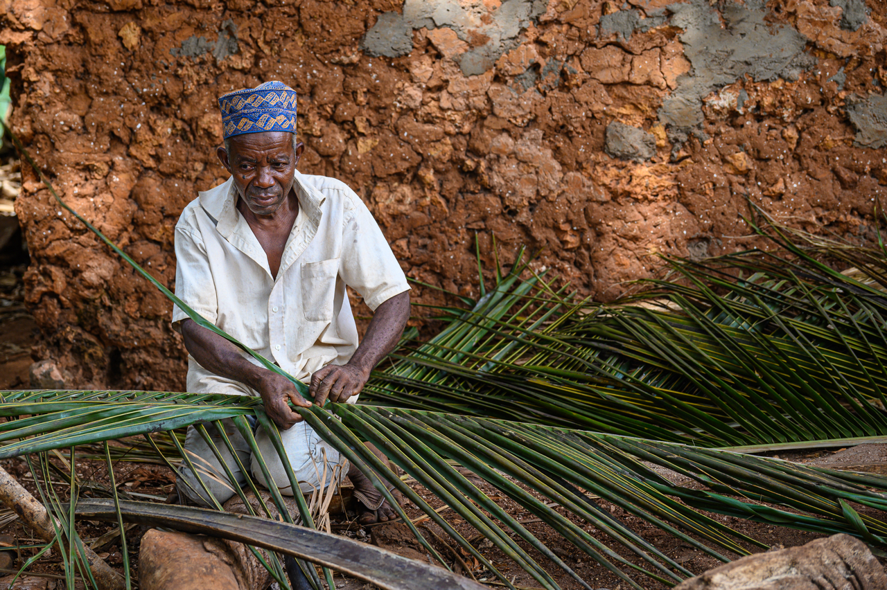 Il capo villaggio mentre intreccia e fronde di palma