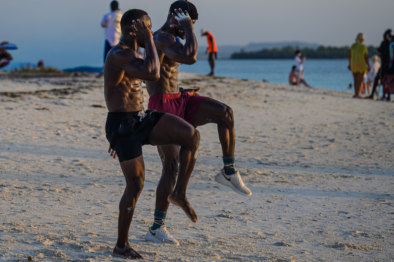 Tra le persone che giocano a pallone, passeggiano, al tramonto, sulla spiaggia di Kendwa c'&egrave; chi fa attivit&agrave; fisica