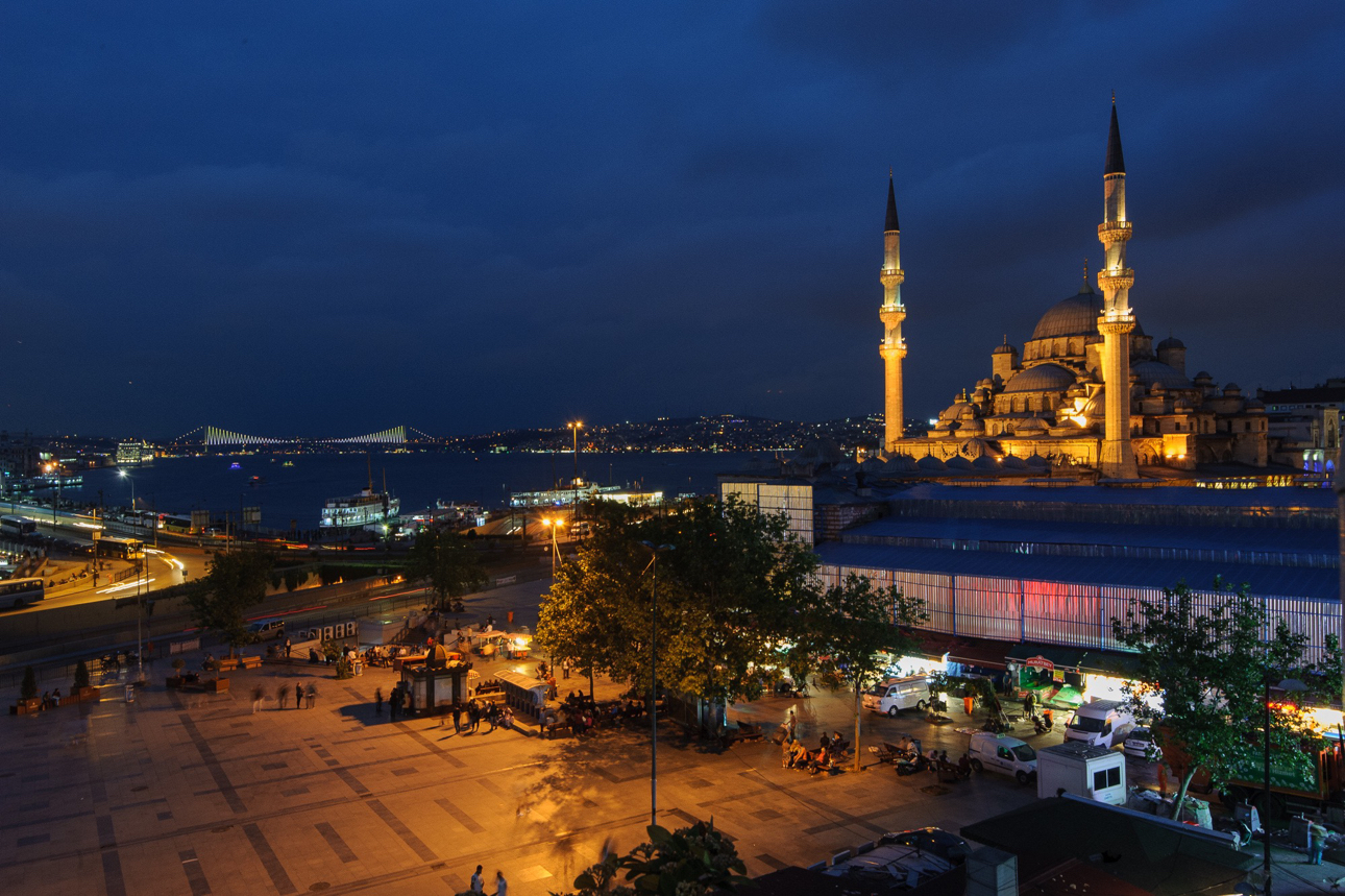 Una panoramica notturna del quartiere di Emin&ouml;n&uuml; la Yeni Camii (Nuova Moschea) illuminata in primo piano e il Ponte di Galata e il Ponte sul Bosforo sullo sfondo.